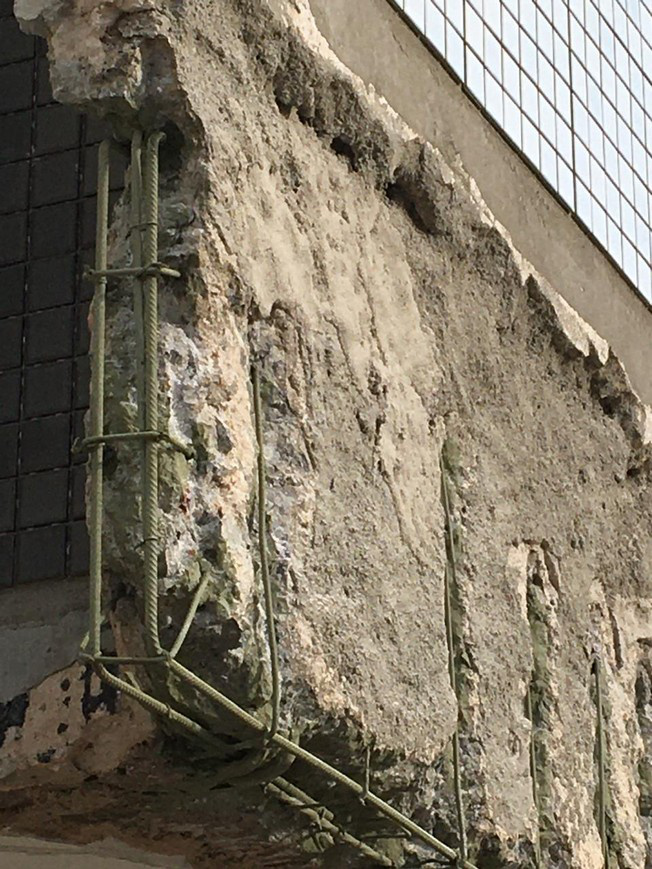 Slab edge with the concrete cover removed along the nose and soffit, exposing the corner reinforcing cage and stirrups