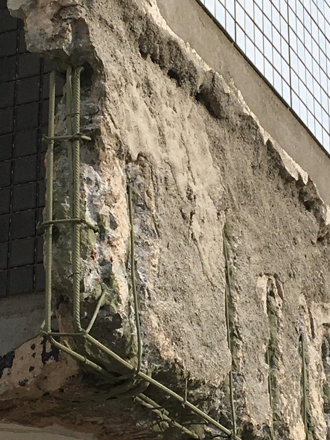 Reinforcing steel exposed after concrete removal with a green coating visible on portions of the bars