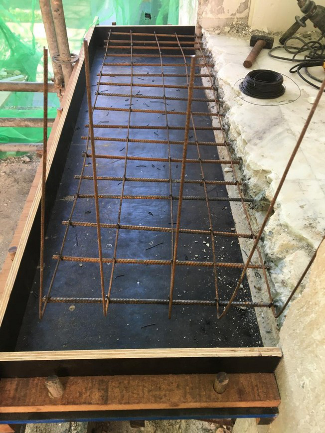 Timber formwork lined and set around a removed concrete section with a mat of reinforcing bars tied inside it