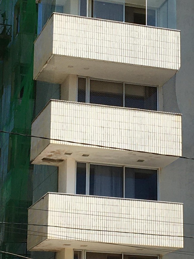 Balcony slab undersides and edges with visible detachments, peeling finishes and areas of material loss