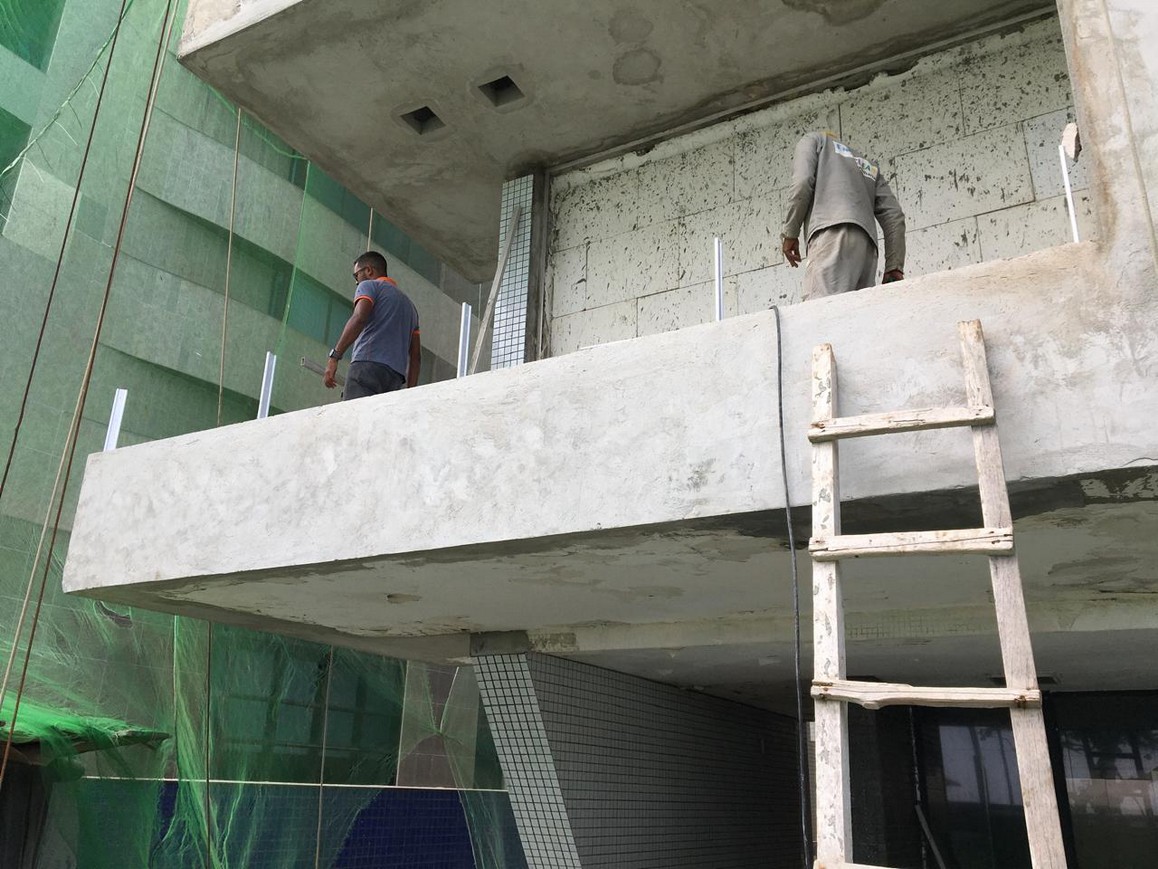 Cantilevered concrete element with reconstructed and regularized faces after repair work