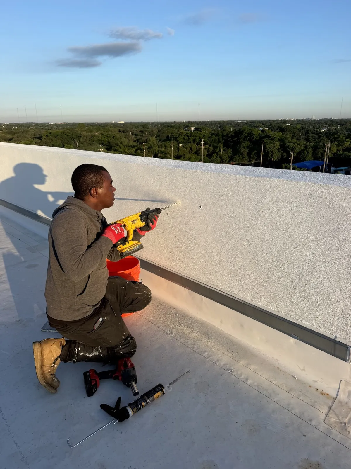 Technician drilling a concrete roof slab to install a rope access anchor